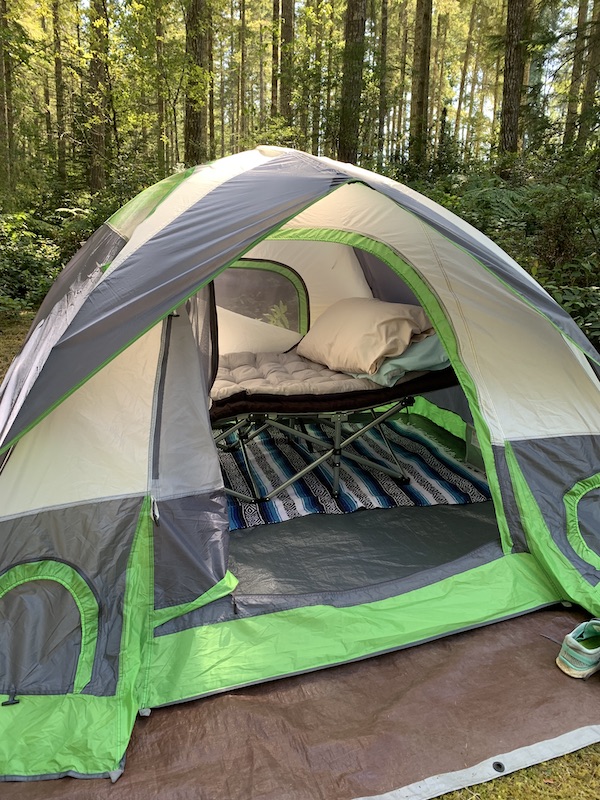 Tent, green and gray exterior, camping cot, blanket, sleeping bag, outdoor setting